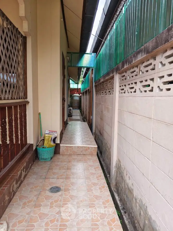 Charming narrow outdoor corridor with tiled pathway and decorative wooden railing, perfect for cozy living.