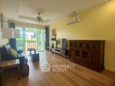Spacious living room with wooden flooring and modern furniture, featuring a balcony view.