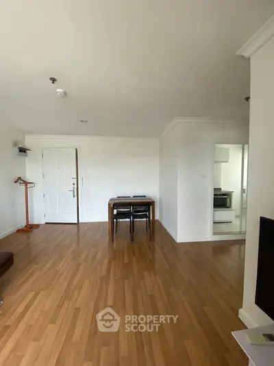 Spacious living room with wooden flooring and dining area in modern apartment.