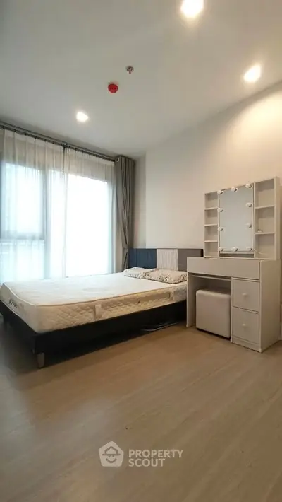 Modern bedroom with large window and stylish vanity in a bright apartment.