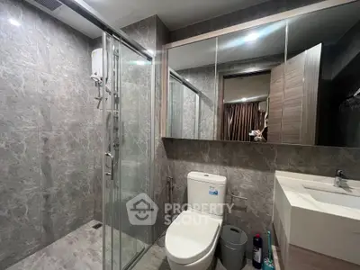 Modern bathroom with glass shower and sleek fixtures in contemporary apartment.