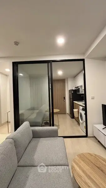 Modern apartment interior with cozy living room and sleek kitchen featuring washing machine and microwave.