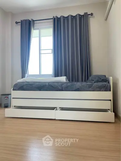 Modern bedroom with sleek white bed and large window, featuring elegant curtains and wooden flooring.