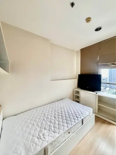 Cozy bedroom with single bed and TV, offering a bright city view through large window.