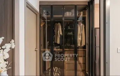 Stylish modern walk-in closet with glass doors and elegant design.