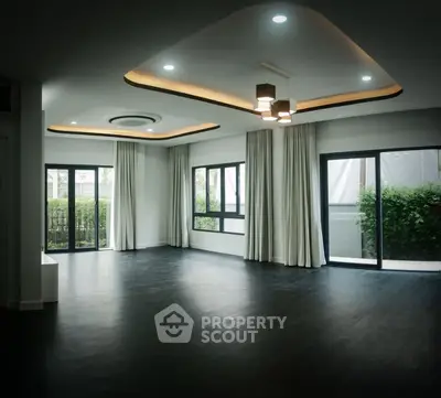 Spacious modern living room with large windows and elegant ceiling lights.
