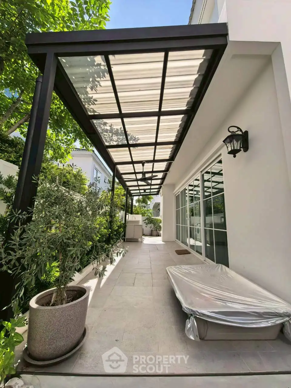 Charming outdoor patio with modern pergola and lush greenery, perfect for relaxation and entertaining.