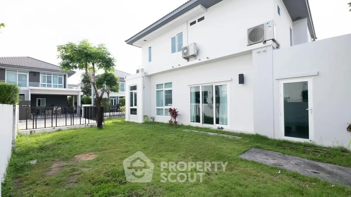 Modern two-story house with spacious green backyard and large windows