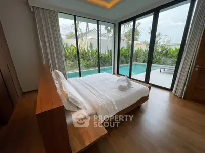 Luxurious bedroom with pool view and floor-to-ceiling windows in modern villa.
