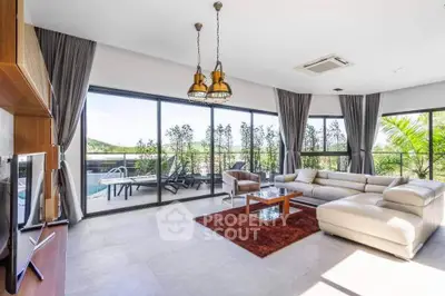 Luxurious living room with pool view and modern furnishings, featuring large windows and elegant decor.