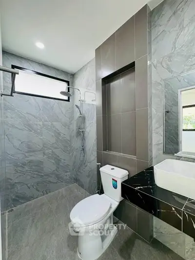 Modern bathroom with sleek design, featuring a stylish shower and elegant sink area.