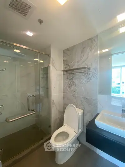 Modern bathroom with glass shower and sleek fixtures in bright apartment
