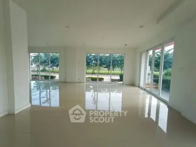 Spacious open-plan living area with large windows offering lush garden views, perfect for modern living.