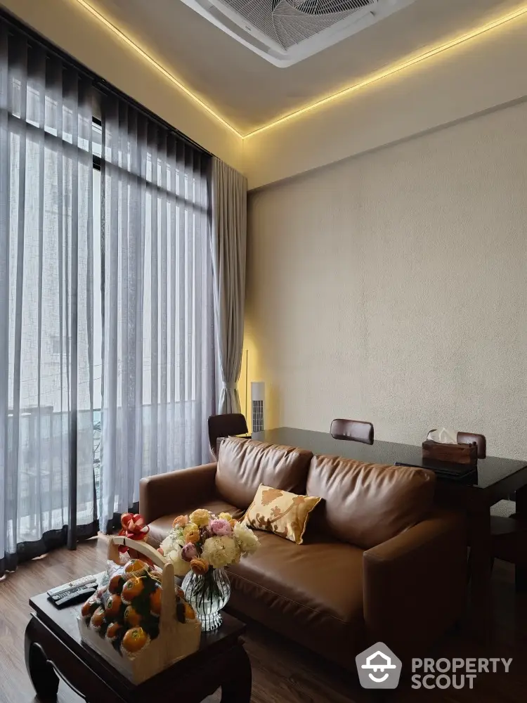 Elegant living room with modern leather sofa, ambient lighting, and floor-to-ceiling windows draped in sheer curtains, creating a warm, inviting atmosphere.