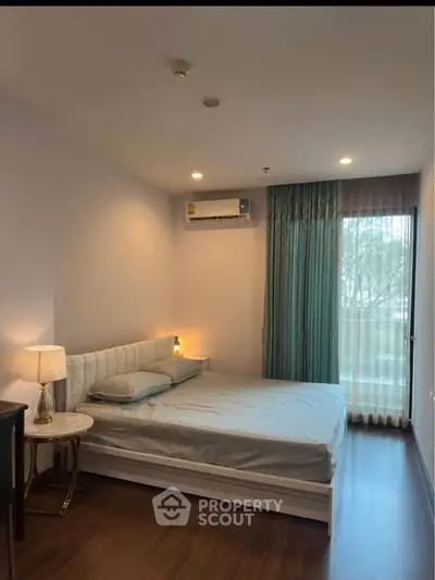 Cozy bedroom with modern furnishings and large window for natural light.