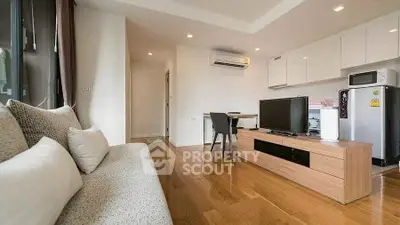 Modern living room with sleek furniture and wooden flooring, featuring a cozy sofa and entertainment unit.