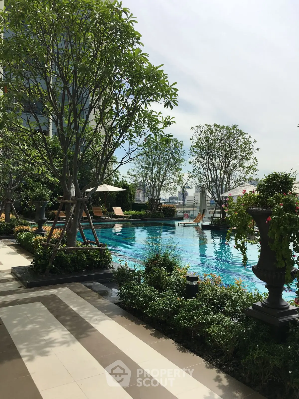 Luxurious rooftop pool with lush greenery and city skyline views, perfect for relaxation and leisure.