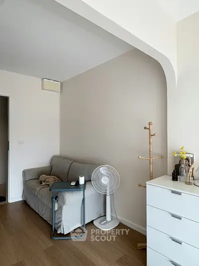 Cozy living room with modern decor, featuring a comfortable sofa, fan, and stylish coat rack.
