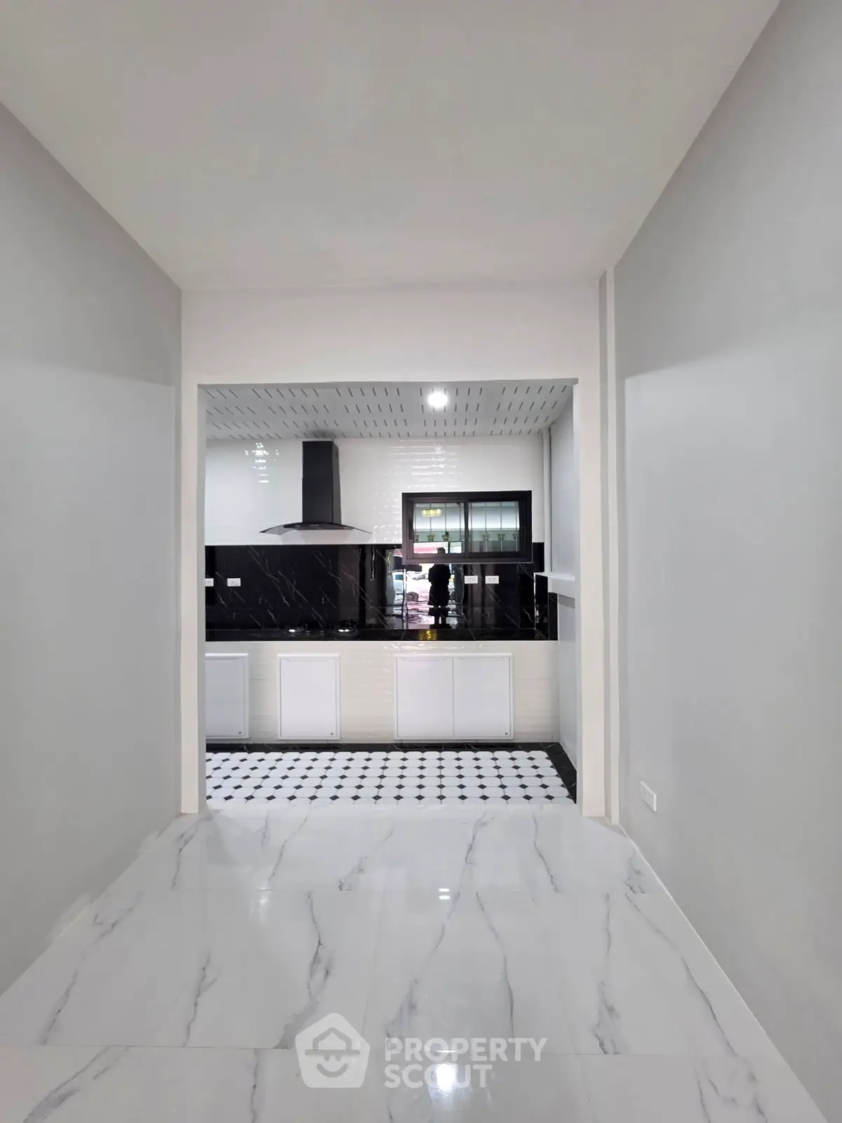 Modern kitchen with sleek black and white design, featuring a gas stove and elegant flooring.