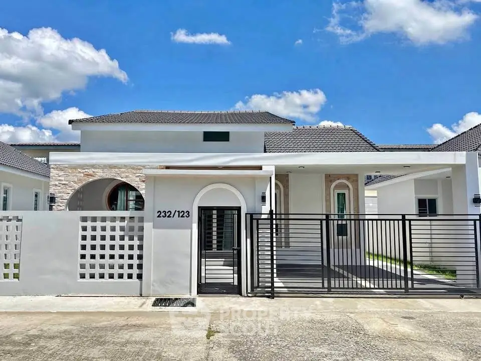 Modern single-story house with gated entrance and stylish facade under a clear blue sky.