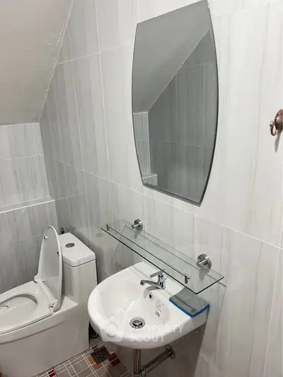 Modern bathroom with sleek fixtures and elegant tiling, featuring a stylish mirror and compact sink.