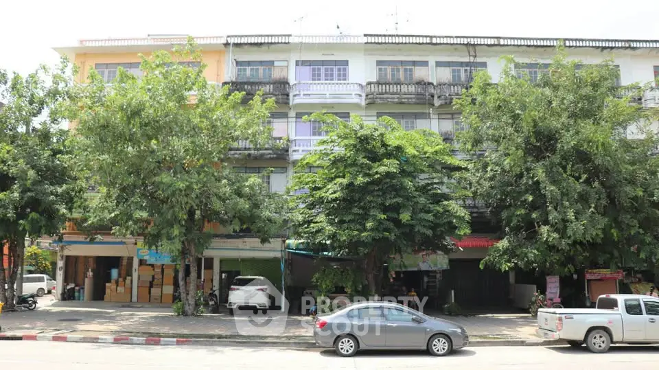 Charming multi-story building with lush greenery and street view, ideal for urban living.