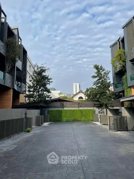 Modern residential building exterior with lush greenery and spacious driveway.
