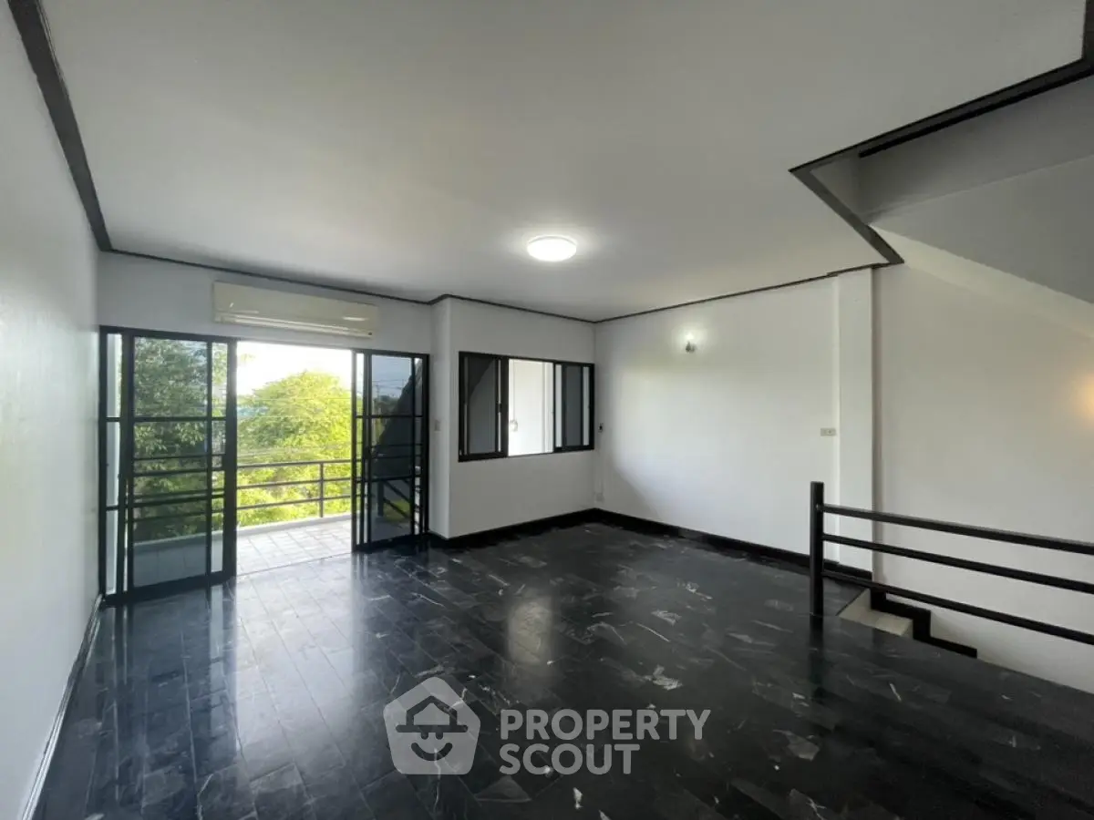 Spacious modern living room with dark flooring and balcony access