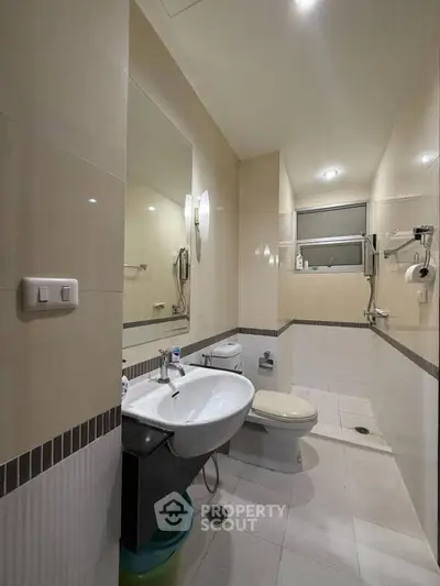 Modern bathroom with sleek fixtures and neutral tiles, featuring a spacious layout and contemporary design.