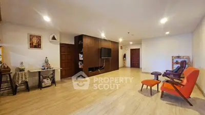 Spacious living room with modern decor and wooden flooring, featuring stylish seating and a wall-mounted TV.