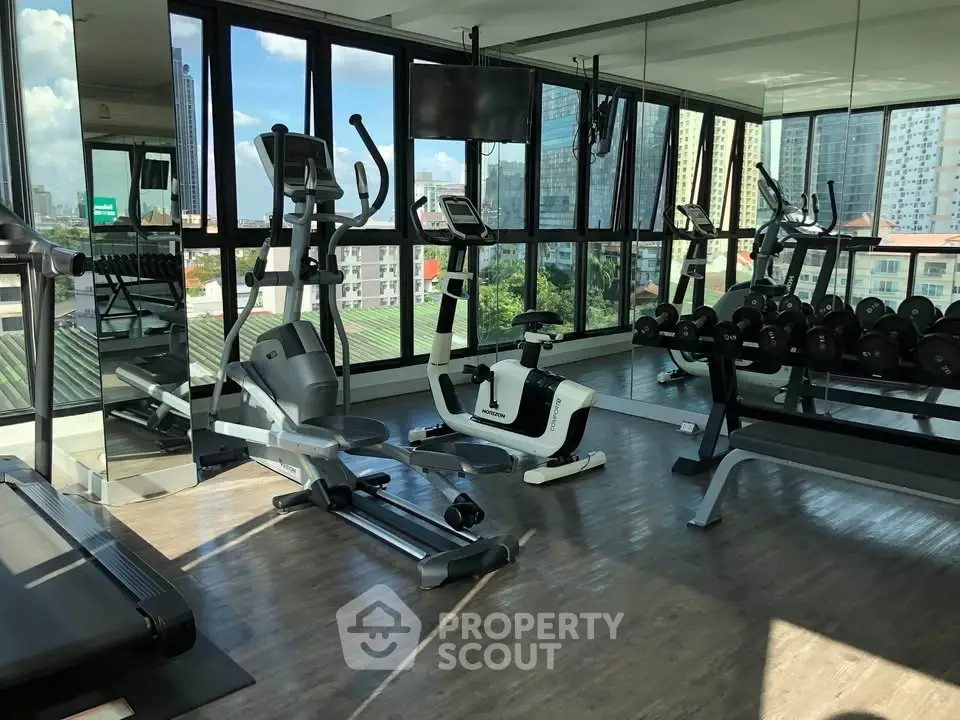 Modern gym with city view, featuring state-of-the-art exercise equipment and floor-to-ceiling windows.