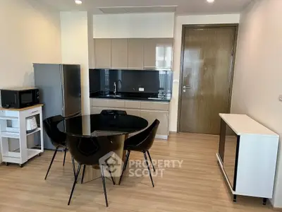 Modern kitchen with sleek cabinetry, dining area, and stainless steel appliances in a stylish apartment.