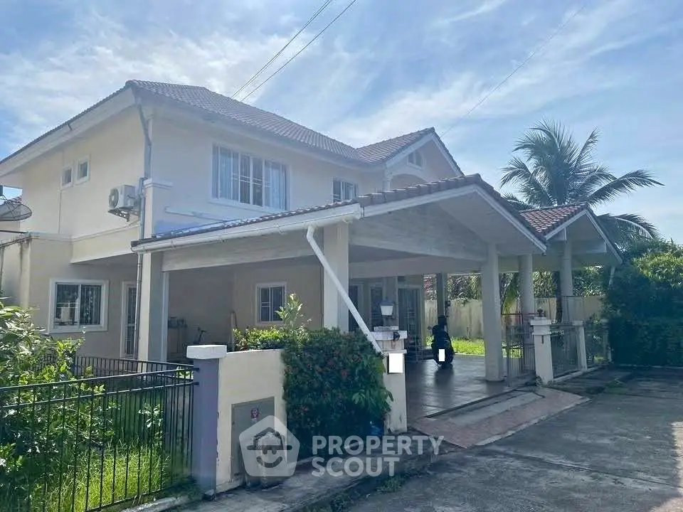Charming two-story house with spacious carport and lush greenery