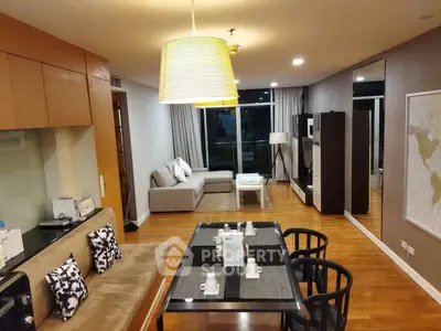 Spacious modern living room with stylish decor and dining area, featuring wooden flooring and ambient lighting.