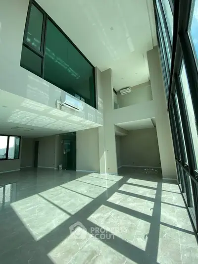 Spacious modern living room with high ceilings and large windows offering abundant natural light.