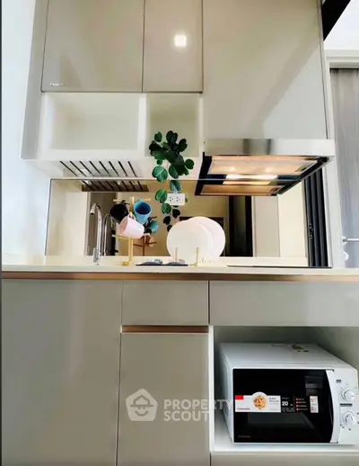 Modern kitchen with sleek cabinetry and built-in microwave, featuring a stylish open layout.