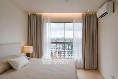 Modern bedroom with city view, featuring large window, neutral decor, and air conditioning.