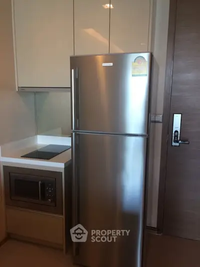 Modern kitchen with stainless steel fridge and built-in microwave in sleek apartment.