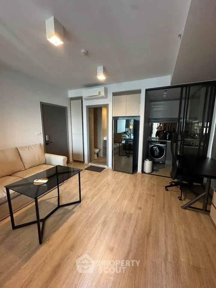 Modern living room with sleek furniture and integrated laundry area in stylish apartment.