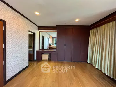 Spacious bedroom with wooden flooring and built-in wardrobe in a modern apartment.