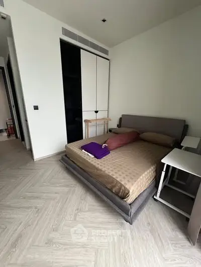 Modern bedroom with stylish herringbone flooring and sleek furniture design.