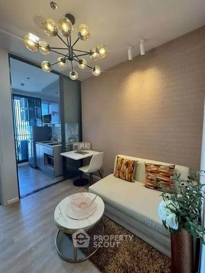 Modern living room with stylish lighting and cozy seating area, adjacent to a sleek kitchen.