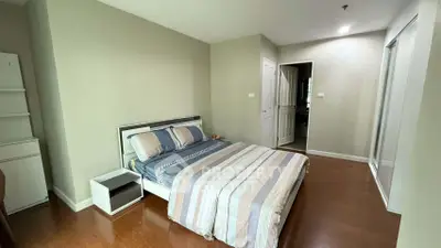 Spacious bedroom with modern decor and wooden flooring in a cozy apartment.