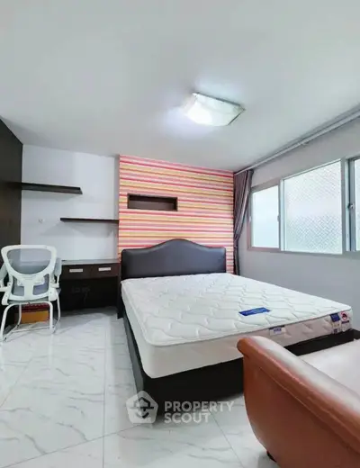 Spacious bedroom with modern furnishings and large window for natural light.