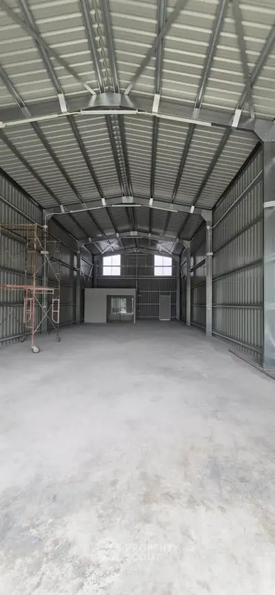 Spacious industrial warehouse with high ceilings and metal structure, ideal for storage or manufacturing.