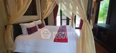 Luxurious bedroom with canopy bed and elegant decor in tropical setting.