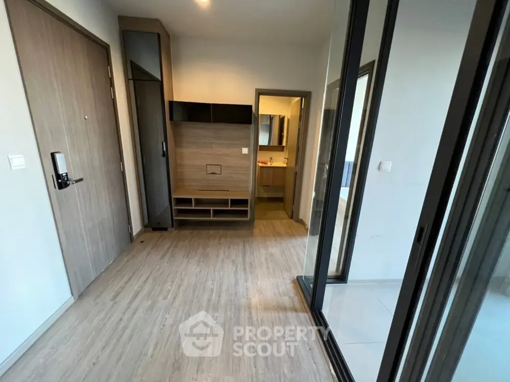 Modern apartment entrance with sleek wooden flooring and mirrored closet