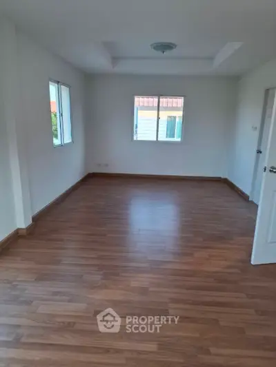 Spacious empty room with wooden flooring and natural light