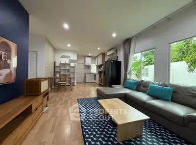 Spacious modern living room with open kitchen, stylish decor, and natural light.