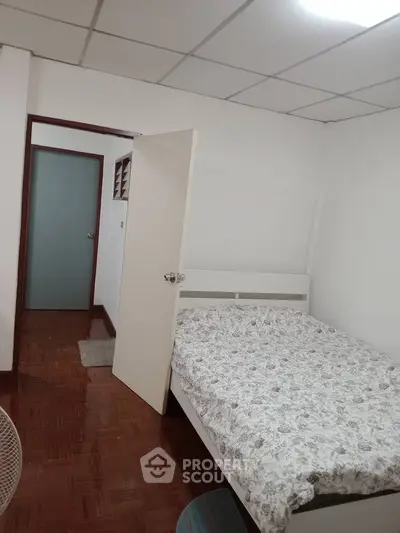 Cozy bedroom with floral bedding and parquet flooring in a minimalist design.